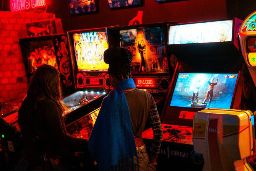 pessoas a jogarem jogos em máquinas arcade