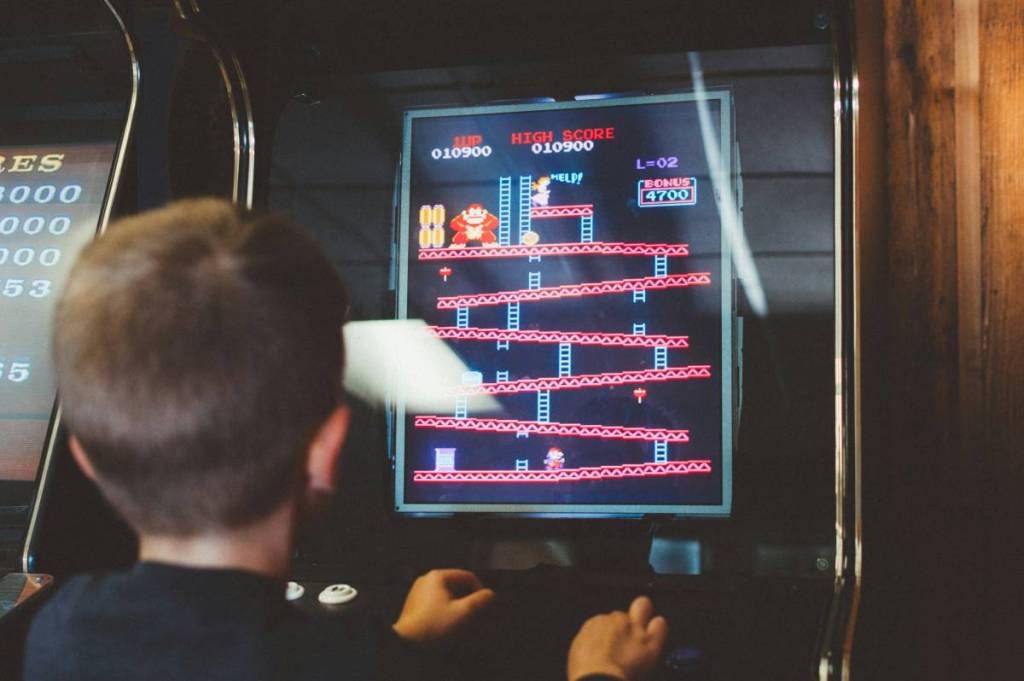 criança a jogar jogos em máquinas arcade
