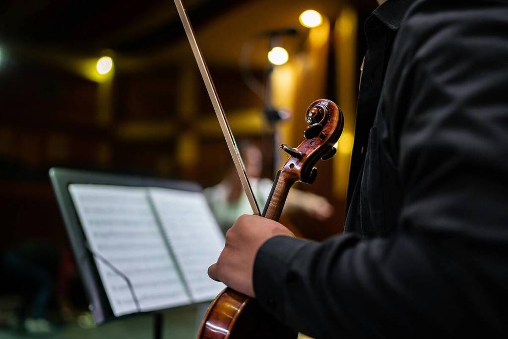 Homme tenant un violon dans ses mains, suivant une partition de musique
