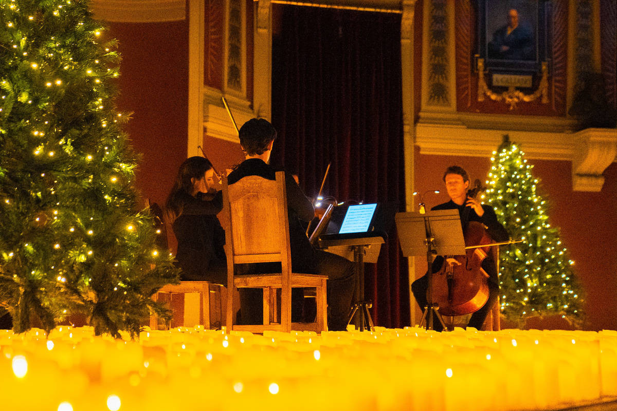 Un cuarteto de cuerda toca sobre un escenario cubierto de velas durante un concierto Candlelight dedicado a la Navidad en el Ateneo de Madrid.