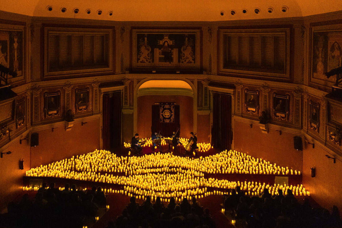 Un cuarteto de cuerda toca sobre un escenario cubierto de velas durante un concierto Candlelight en el Ateneo de Madrid.