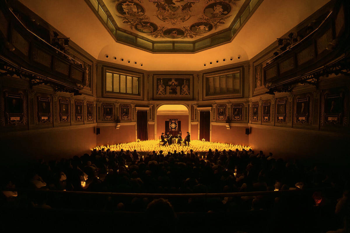 Un cuarteto de cuerda toca sobre un escenario cubierto de velas durante un concierto Candlelight en el Ateneo de Madrid.