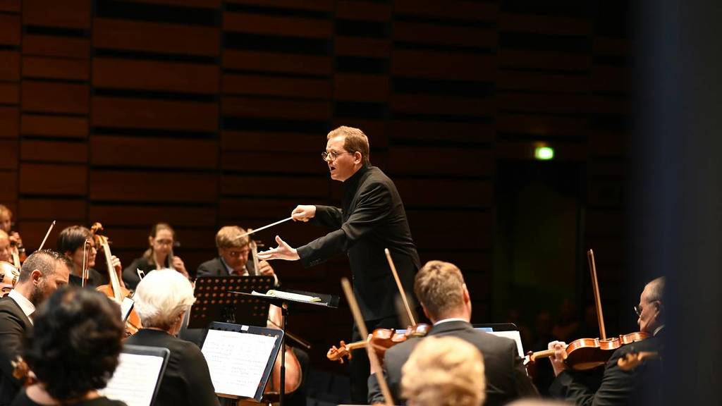Plan moyen d'un chef d'orchestre dirigeant un orchestre.