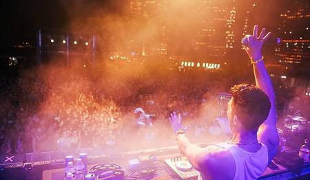 DJ cheering the audience with his arm in the air during a great disco concert in Madrid.