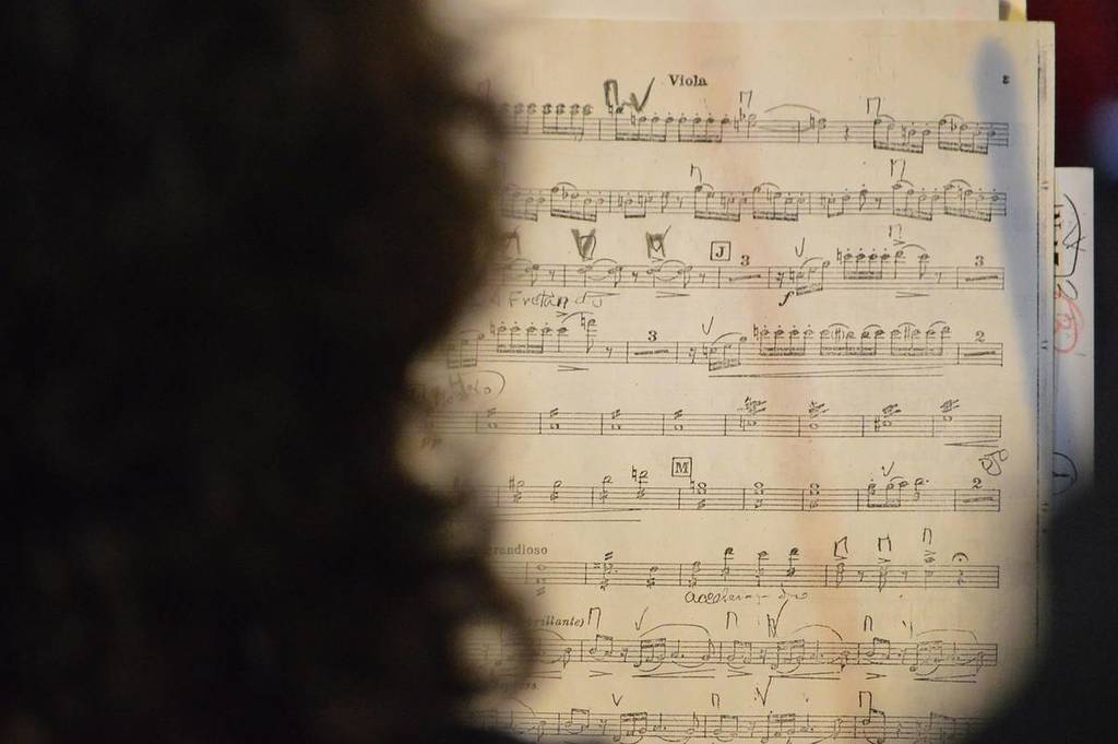 Primo piano di uno spartito musicale per viola durante un concerto di un'orchestra.