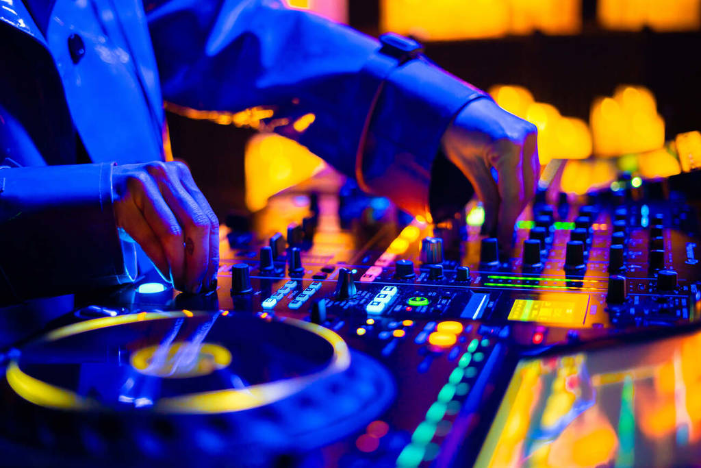 Primer plano de las manos del DJ sobre el set en un escenario cubierto de velas durante un concierto Candlelight Beats.