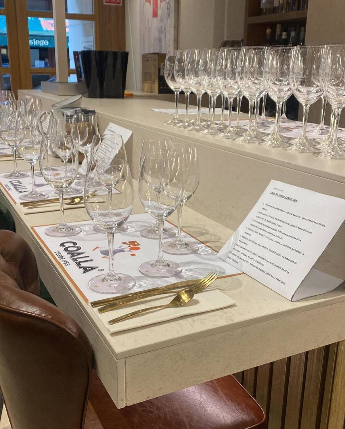 Weinverkostungsbar mit aufgereihten Gläsern und Verkostungszetteln in einem Fachgeschäft in Madrid.