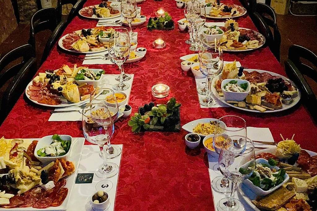 Langer Tisch, gedeckt für eine Weinverkostung in Madrid mit Gläsern, Kerzen und Platten mit Wurstwaren, Käse und verschiedenen Tapas.