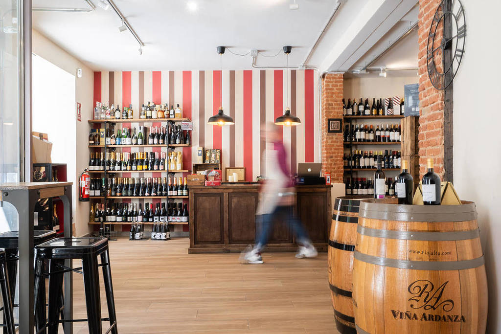 Innenansicht eines Weinladens in Madrid mit Regalen voller Flaschen und einem dekorativen Fass von Viña Ardanza.