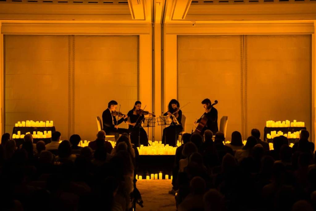 Un cuarteto de cuerda toca sobre un escenario cubierto de velas en el Hotel Four Seasons de Madrid.