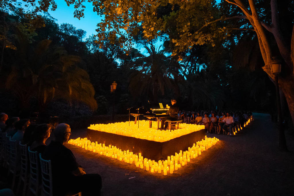 Pianista sobre un escenario elevado y lleno de velas en el Jardín Botánico Histórico La Concepción de Málaga