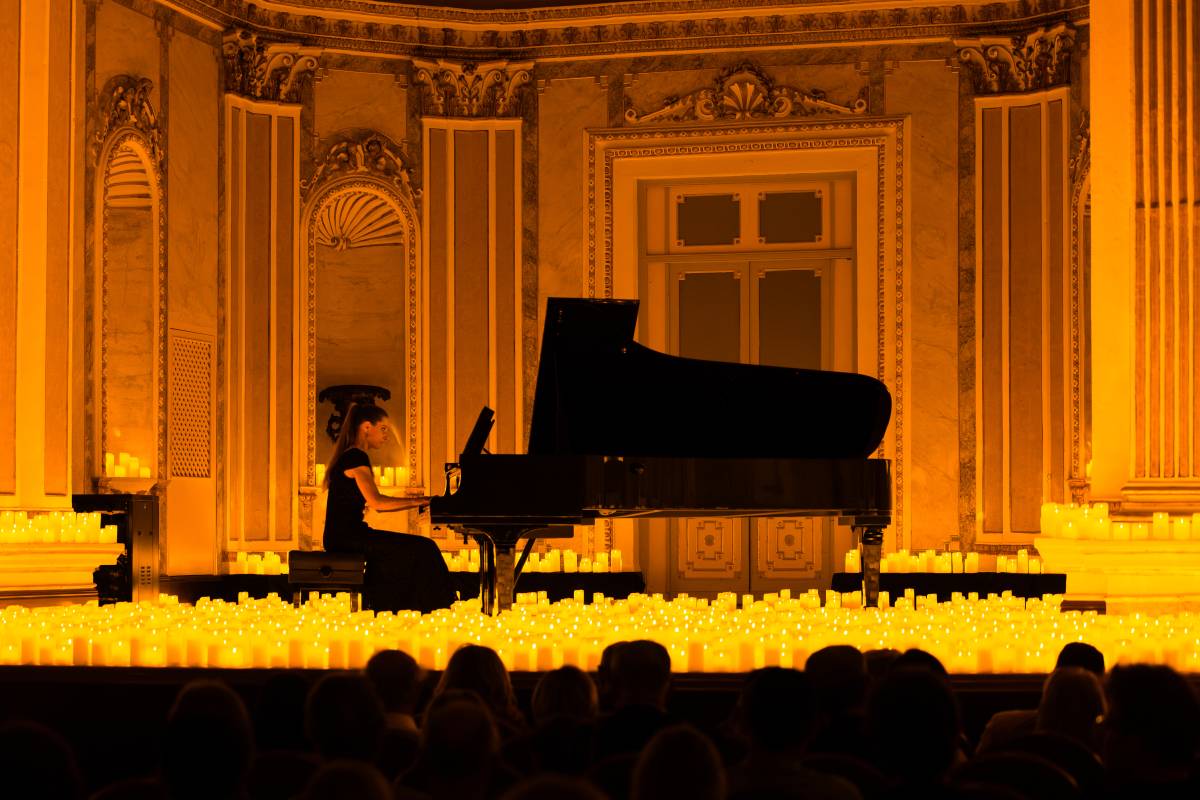 Una pianista toca sobre un escenario cubierto de miles de velas durante un concierto Candlelight en Málaga.
