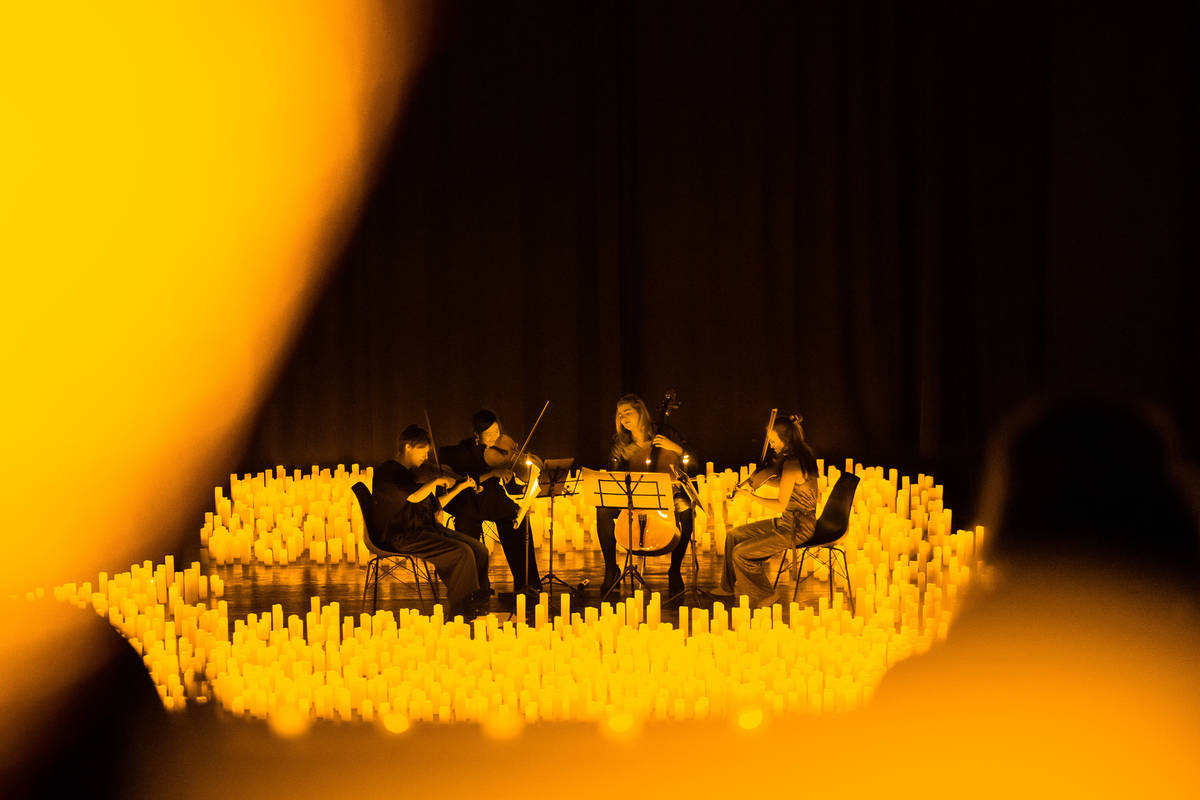 Un cuarteto de cuerda toca sobre un escenario cubierto de velas durante un concierto Candlelight.