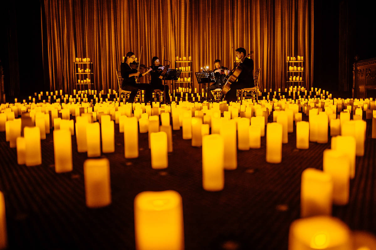Un cuarteto de cuerda toca sobre un escenario cubierto de velas durante un concierto Candlelight.