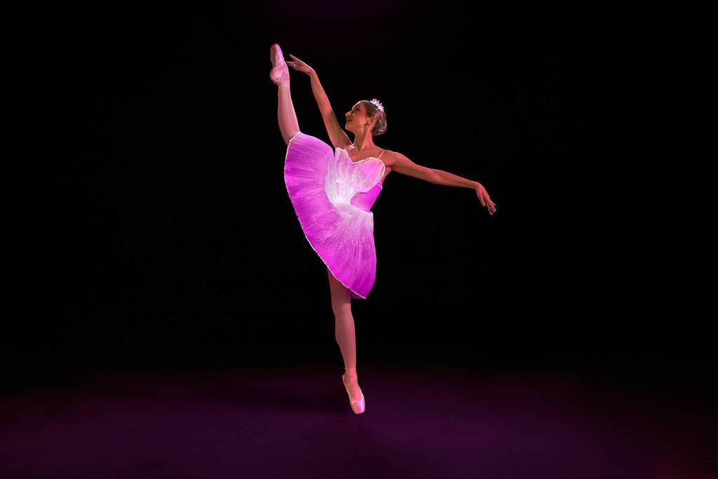Bailarina haciendo una pirueta de ballet mientras brilla en la oscuridad