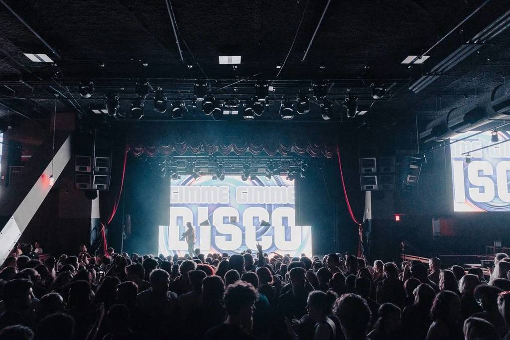 Plano general desde el público, con todo el mundo bailando delante del escenario en 