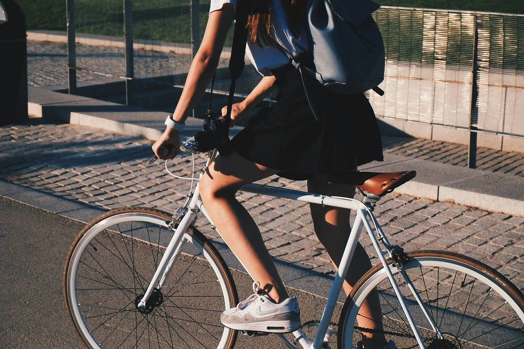 Ragazza va in bicicletta con una bici noleggiata a Milano