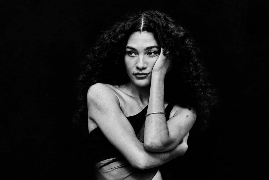 Olivia Dean poses for a black-and-white photo in a semi-sheer dress