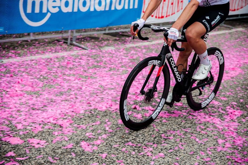 Close-up photo of one of the Giro d’Italia competitors’ bikes crossing a street covered in pink confetti