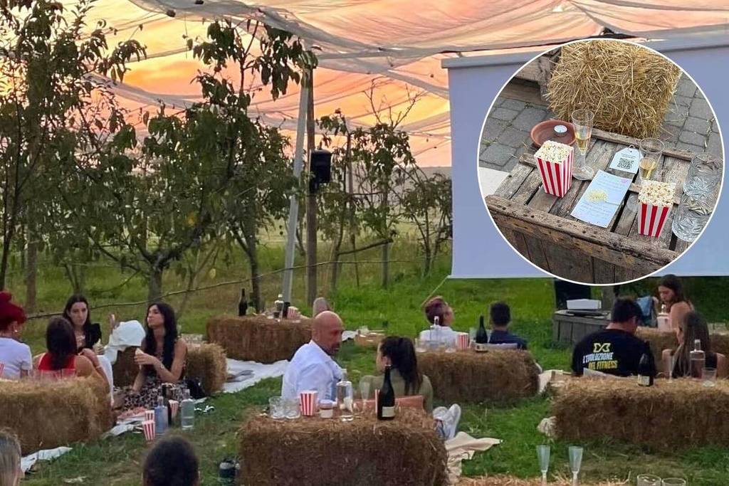 Persone che aspettono l'inizio del film su proiettore in campagna sedute sull'erba
