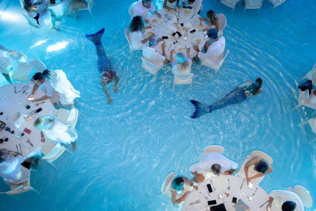 Des sirènes nagent entre les tables dans la piscine de la Villa ReNoir