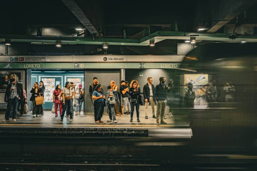 Commuters waiting on the platform at the Loreto subway station (M1) in Milan as a train passes by