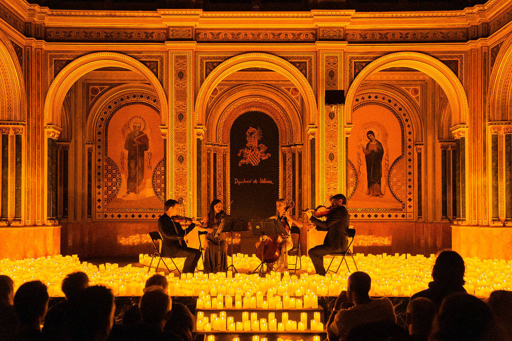A string quartet plays on a candlelit stage during a Candlelight concert.