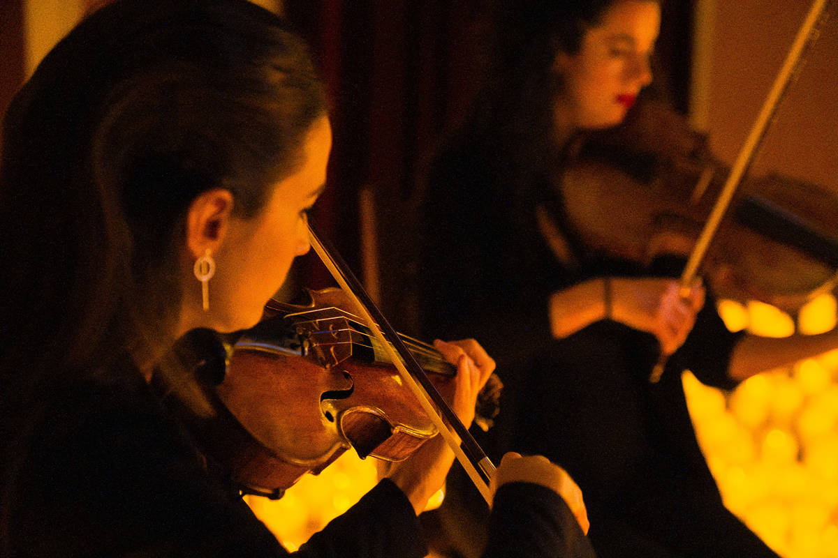 Primer plano de dos violinistas durante un concierto Candlelight de Navidad.