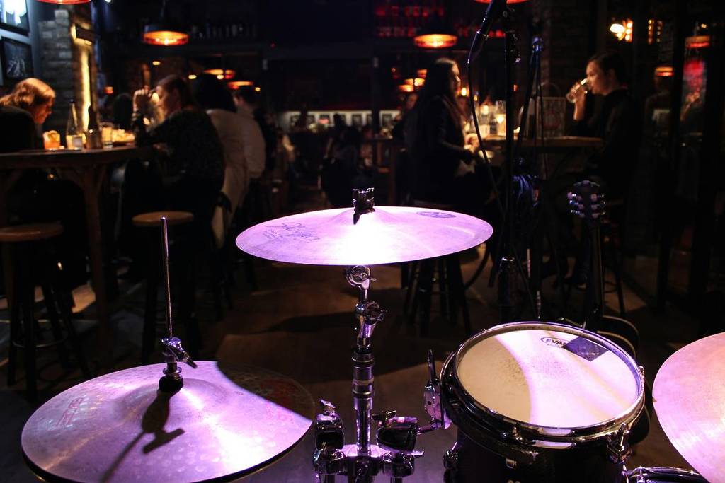 Photo d'un club de jazz avec lumières tamisées et batterie éclairée sur scène