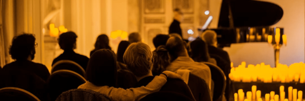 Photo du public de dos écoutant un pianiste jouer des morceaux de musiques pour un concert Candlelight