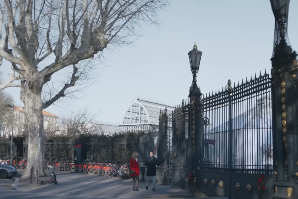 Photo de la scène d'un film où l'on voit un couple se promener devant un parc