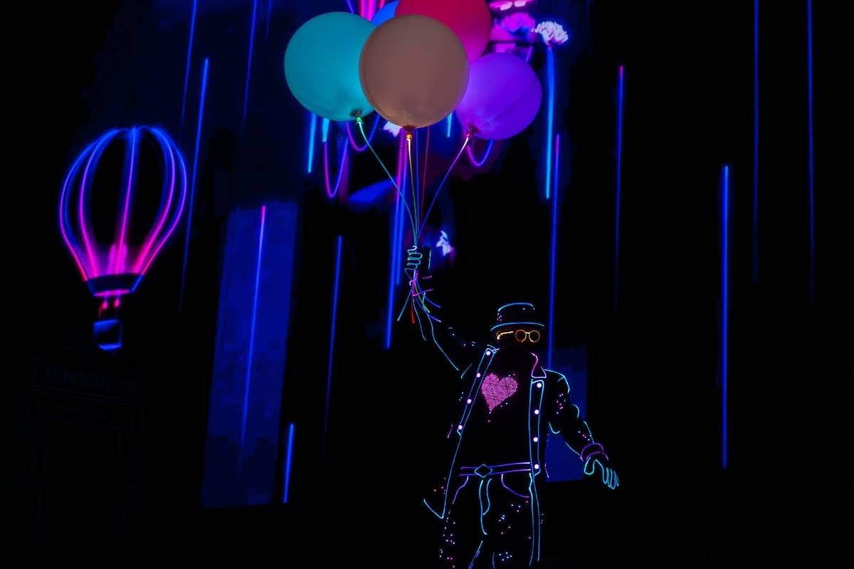 Danseurs avec un costume LED et des ballons lumineux dans le noir
