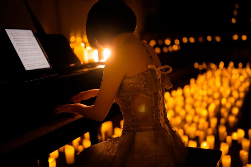 mulher a tocar piano num concerto candlelight à luz de velas