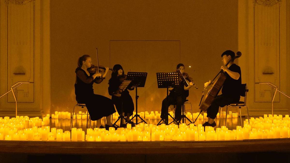 Photo d'un quatuor à cordes en plein concert au mileu de bougies