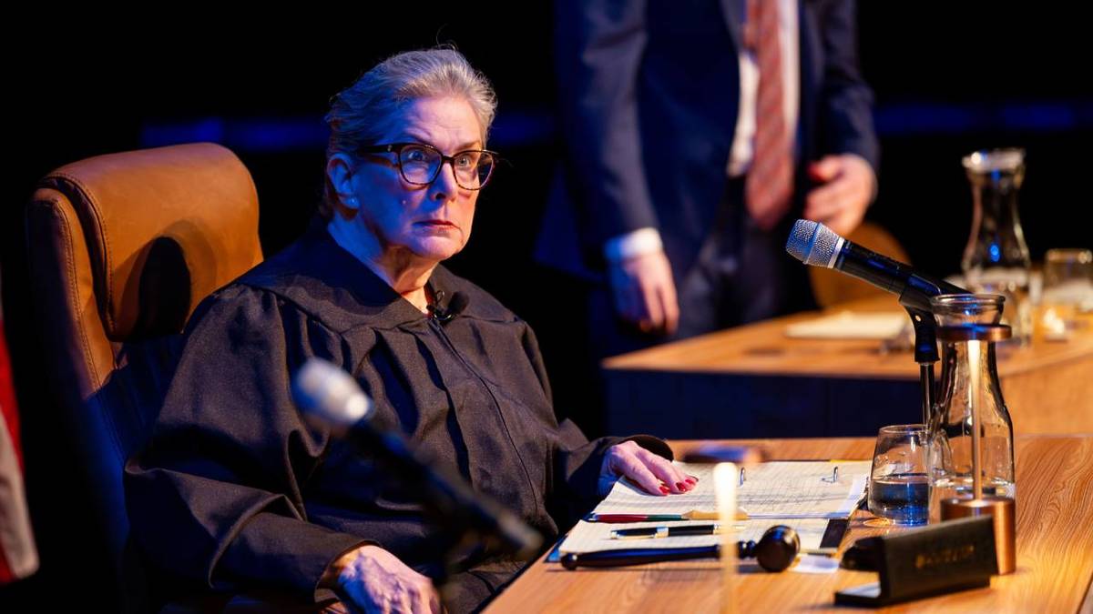 Photo d'une juge assise à un bureau avec des fiches et un marteau posé sur ce bureau