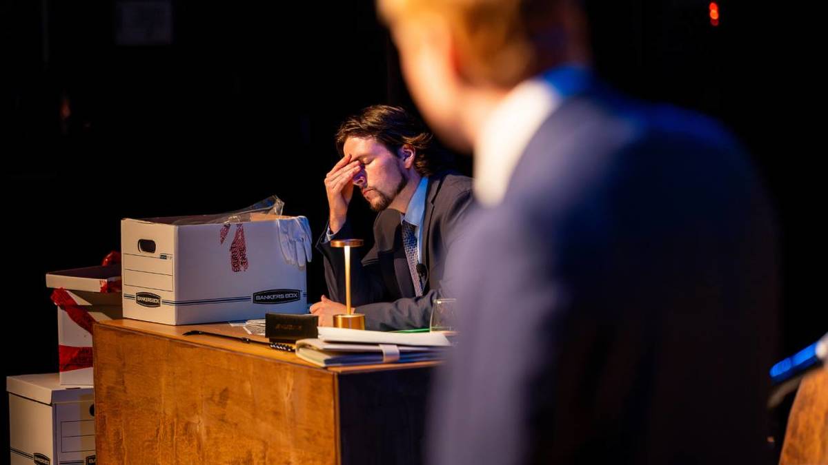 Photo d'une personne accoudée à son bureau avec une autre personne floue en premier plan
