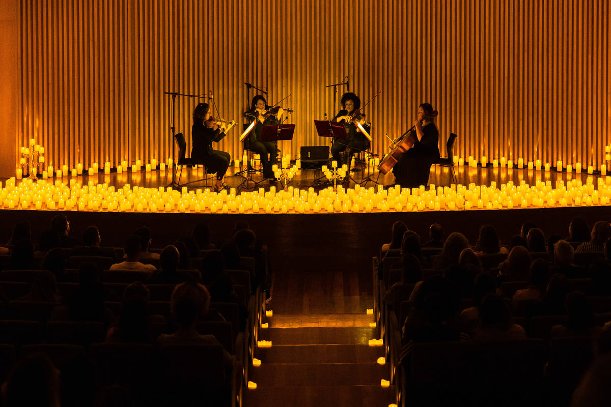 quarteto de cordas em um palco iluminado apenas por milhares de velas no Concerto Candlelight no Museu do Amanhã