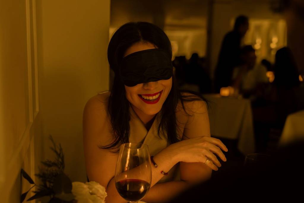 Uma mulher sorrindo com a experiência do Dining in the Dark.