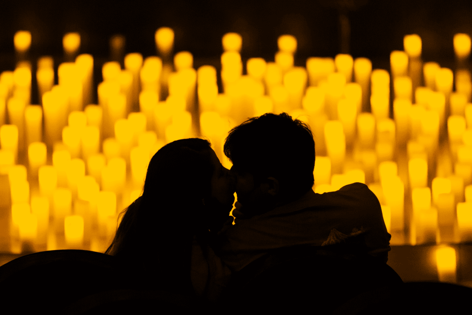 two people kiss at a candlelight concert