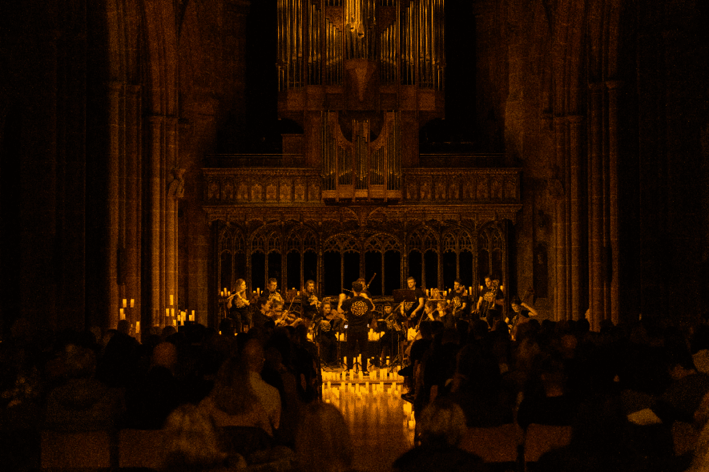 Musicians play in a church amid candles