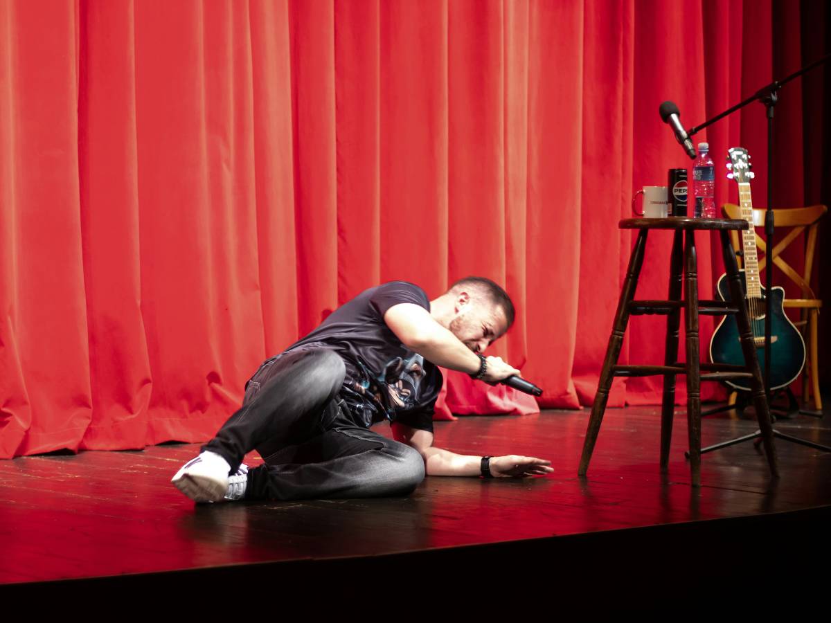 A comedian on the floor on stage at a comedy show - things to do at night Sacramento