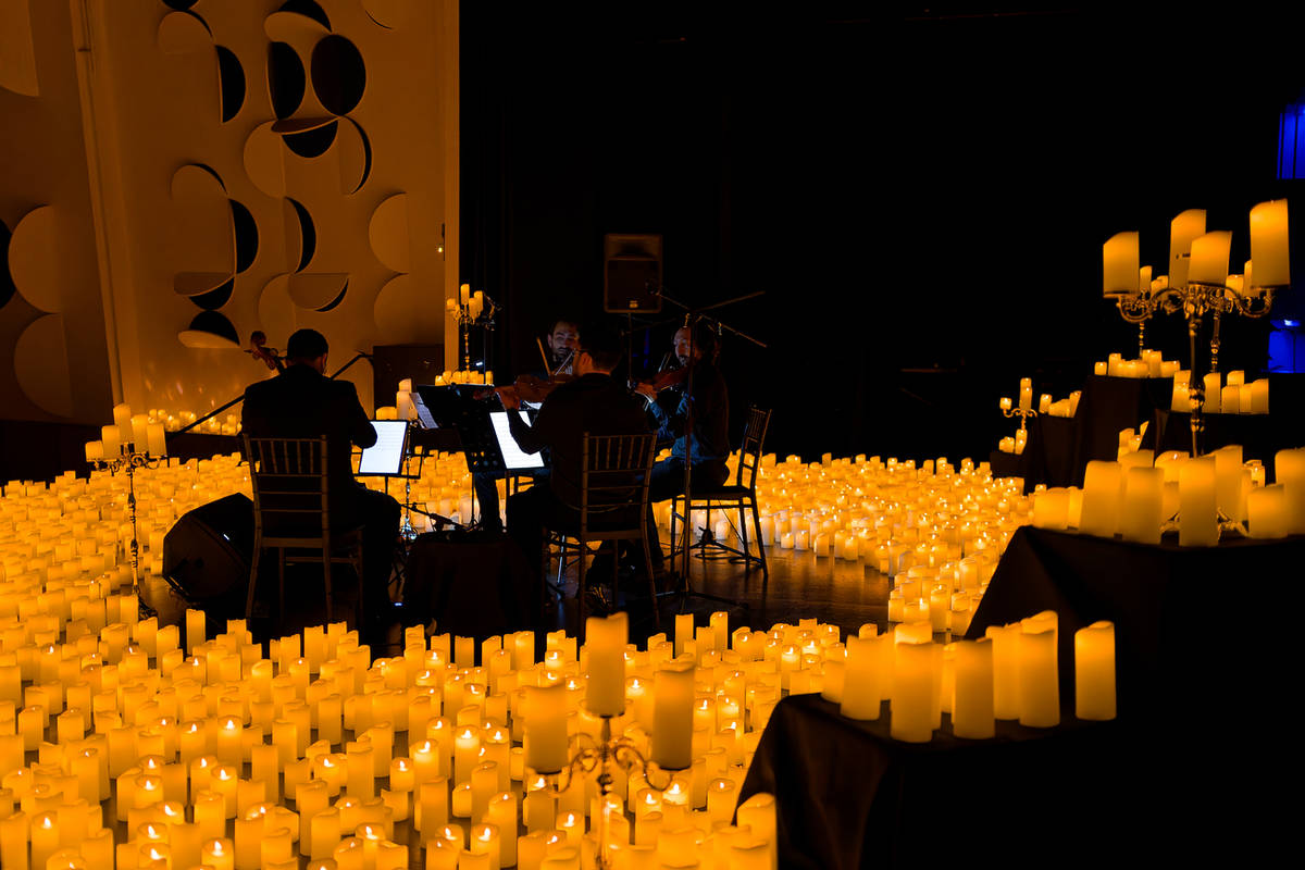 Cuarteto de cuerda tocando en el escenario del Centro Cultural CEINA en Santiago, rodeado por miles de velas