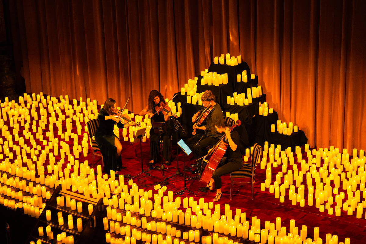 Concierto Candlelight a cuarteto de cuerdas en un teatro con telón rojo e iluminado por miles de velas