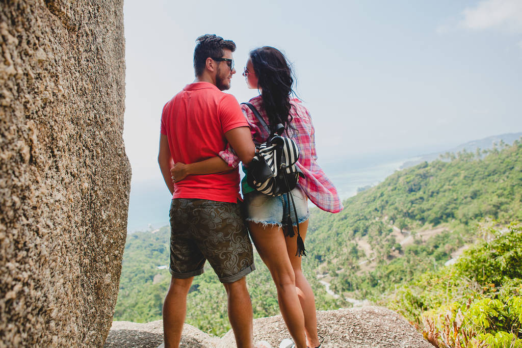 Jovem casal hipster feliz e apaixonado viajando pelo mundo, passeando, férias românticas tropicais na Tailândia, sentados em uma pedra, apontando o dedo, turismo ativo, verão