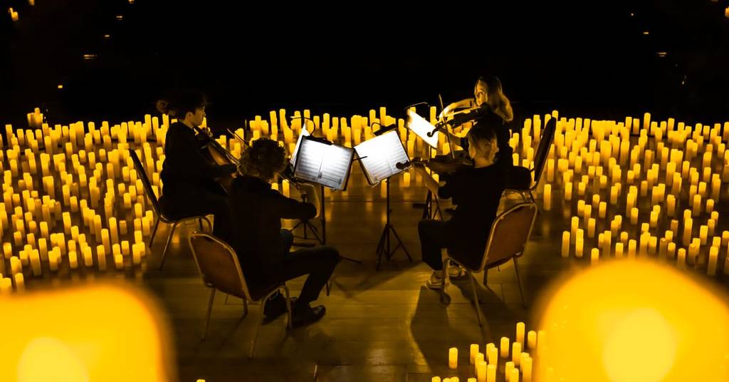 A string quartet performing amid a sea of candles
