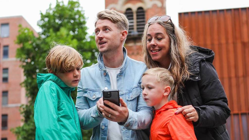 a family of four huddle around a phone on the Race Across The World Experience