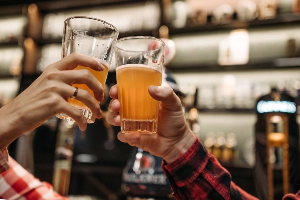 Two people cheering pints in a pub