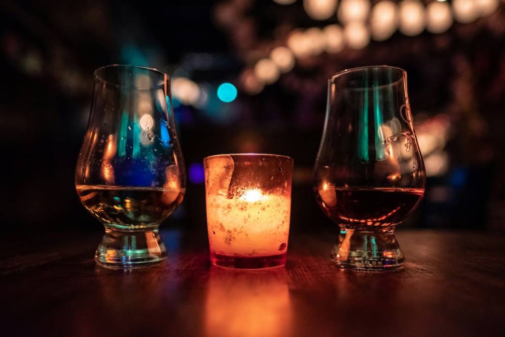 Two drinks next to a candle in a dark bar