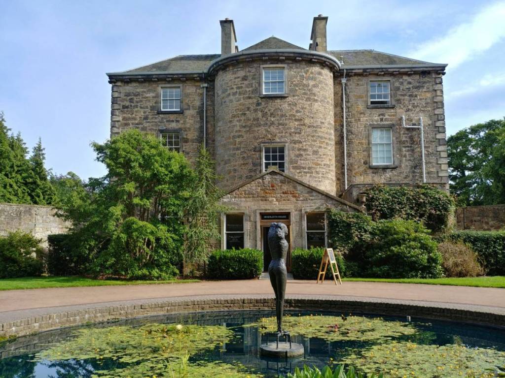 An old brick mansion behind a pond