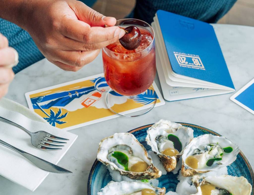 Oysters and a cocktail laid on a table beside an 1820 menu